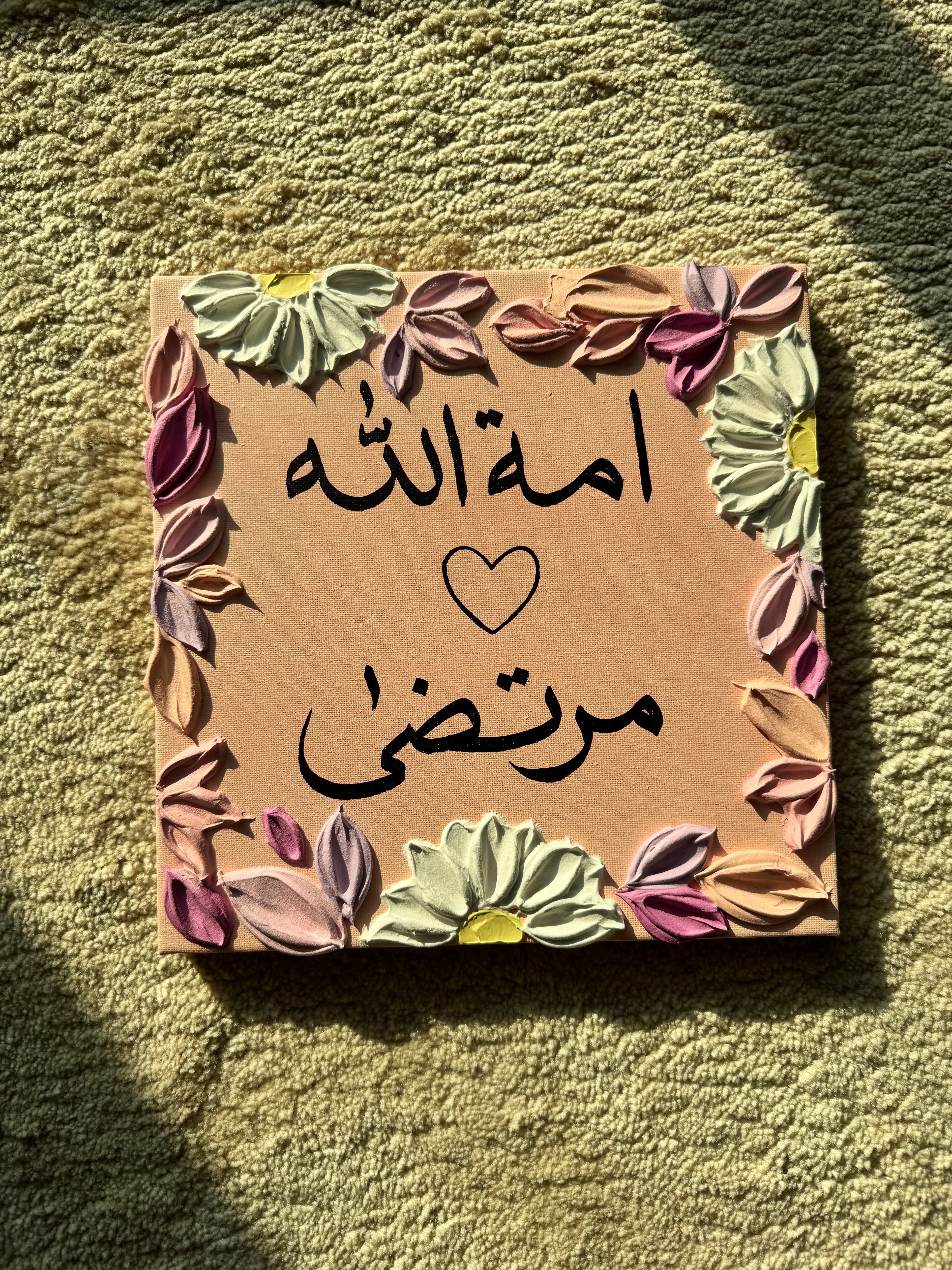 Decorative card with floral border and Arabic text on a textured surface